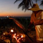 Pescador assando peixe na brasa do coco seco enquanto conta suas histórias