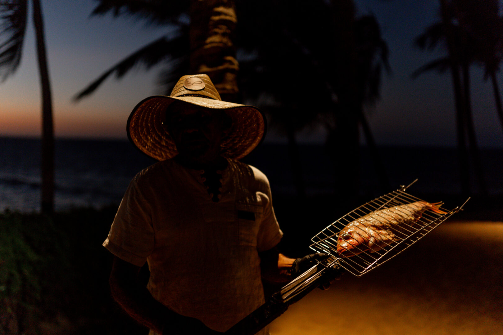 Pescador assando o peixe na experiência do pescado rústico que exalta os sabores da gastronomia cearense.