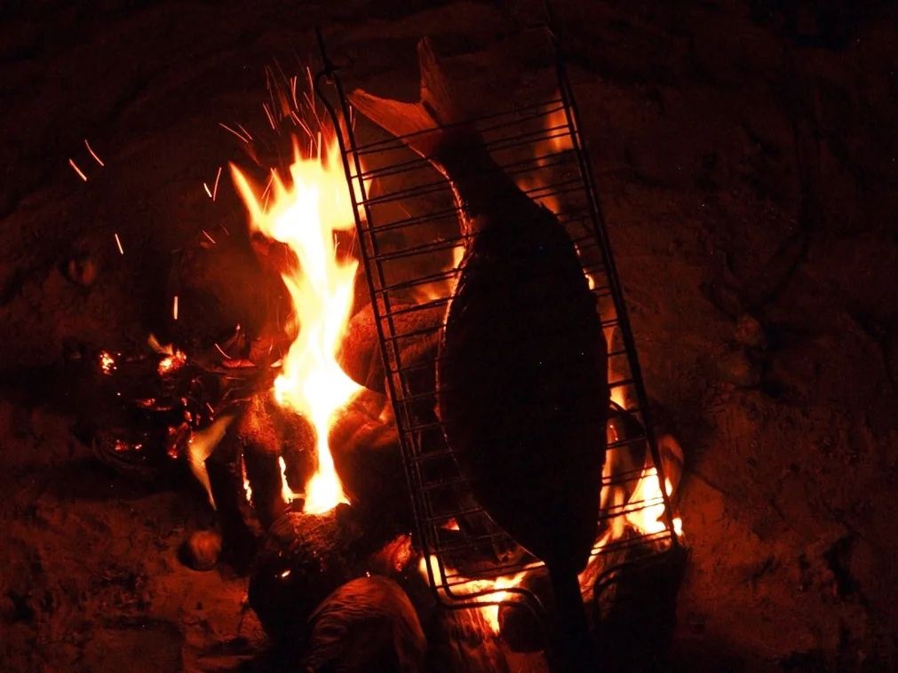 Peixe sendo assado na brasa do coco seco à beira-mar, uma experiência da gastronomia cearense