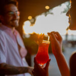 Casal saboreando drinks na beira da piscina